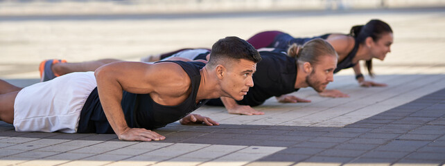 Group of fitness people doing push ups in the city