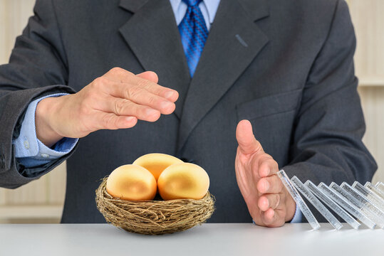 Asset Or Wealth Protection For High Net Worth Individuals, Financial Concept : Investor Uses Hands To Protect 3 Golden Eggs, Depicting A Plan To Avoid Risk And Protect Asset For Sustainable Growth