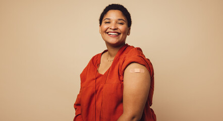 Woman showing her arm after receiving a vaccine - obrazy, fototapety, plakaty