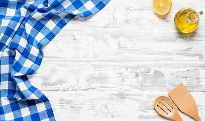 White wooden table covered with blue tablecloth and cooking utensils. View from top. Empty tablecloth for product montage. Free space for your text	