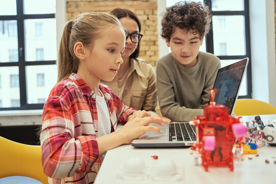 Understand how technology works. Cute little girl learn programming using laptop during STEM class together with young female teacher