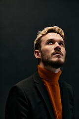Obraz premium stylish blond guy in fashionable clothes on a dark background orange sweater jacket model close-up