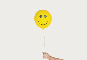 Hand holding smiling face yellow balloon, isolated on white background - 425213665