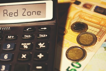 Calculator with the sign Red Zone and euros banknotes concept of coronavirus economic impact