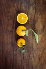 Few juicy oranges with leaves placed in a row on wooden background. Organic, healthy samples of fresh orange fruit.