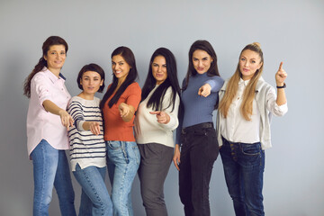 Obraz premium We need you to join us. Group portrait of happy positive young women standing in studio, smiling and pointing fingers at camera, choosing you and inviting you to become member of their successful team