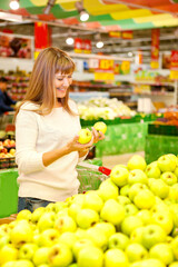 woman in a supermarket at the vegetable shelf shopping for groceries, she is choosing