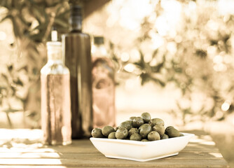 green olives and oil on table in olive grove