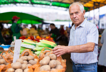 european senior buying potatoes in market