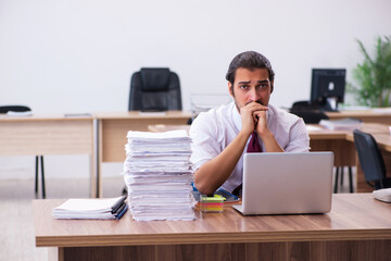 Young male employee unhappy with excessive work in the office