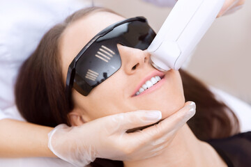 Master carries out removal moustache of unwanted hair laser on face young woman. Concept health and beauty