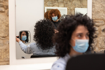 Hairdresser talks to client when checking final appearance