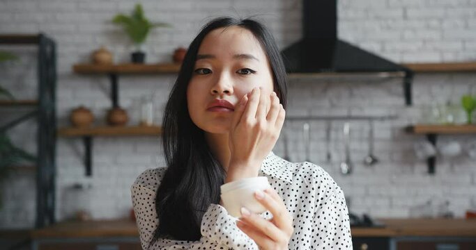 Asian korean beauty blogger woman filming daily makeup routine tutorial. Influencer lady live streaming cosmetics product review in home studio