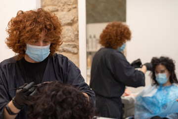 Curly hairdresser with facemask working and mirroring