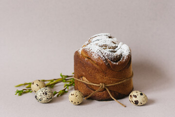 Easter holiday card. Sweet cake with powdered sugar and colored chicken eggs on a light beige background with green branches