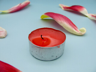An extinguished candle sprinkled with red tulip petals
