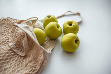 Zero waste shopping concept. Fresh vegetables in eco cotton bags on table in the kitchen. View from above on eco friendly bag filled with green organic apples, zero waste informed consumption concept