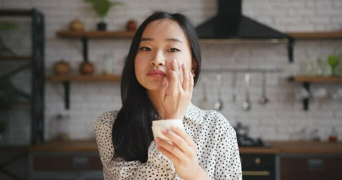 Asian korean beauty blogger woman filming daily makeup routine tutorial. Influencer lady live streaming cosmetics product review in home studio