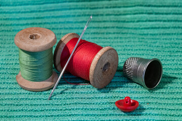 different colored thread, needle, thimble and button. it's all taken close-up