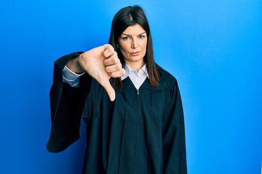 Young hispanic woman wearing judge uniform looking unhappy and angry showing rejection and negative with thumbs down gesture. bad expression.