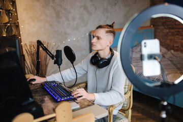 Man recording video on smartphone during the work at home on computer. Young guy recording on...