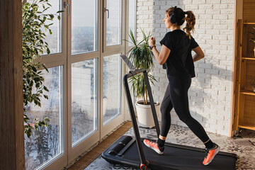 Woman jogging on the modern compact treadmill at home