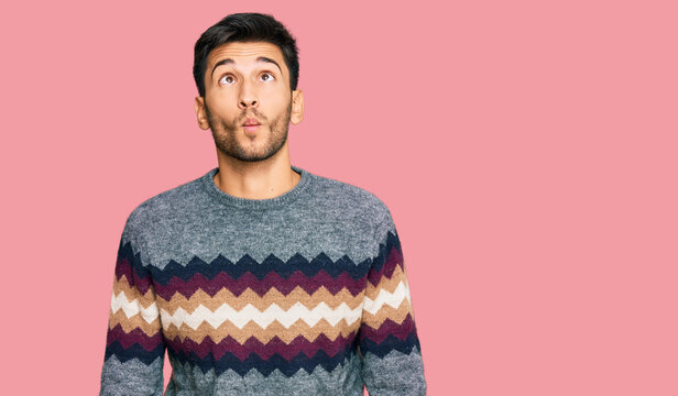 Young handsome man wearing casual winter sweater making fish face with lips, crazy and comical gesture. funny expression.