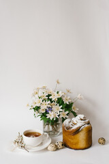 Easter sweet bread, cake and eggs with white apple flowers and primroses, a cup of tea. Festive breakfast concept with copy space.