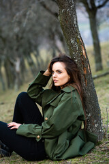 Image of young beautiful woman wearing rain jacket in cold weather. Thinker european girl in spring nature.