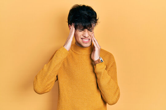 Handsome hipster young man wearing casual yellow sweater with hand on head, headache because stress. suffering migraine.