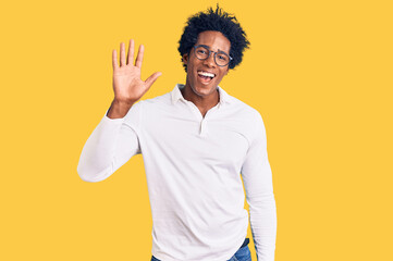 Handsome african american man with afro hair wearing casual clothes and glasses waiving saying hello happy and smiling, friendly welcome gesture