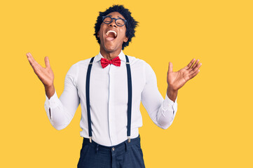 Handsome african american man with afro hair wearing hipster elegant look celebrating mad and crazy for success with arms raised and closed eyes screaming excited. winner concept