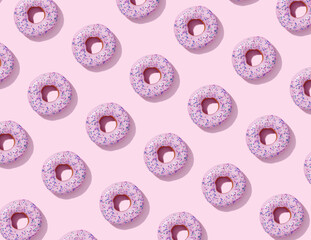 Flat lay pattern with sweet donuts with pink glaze and colorful sprinkles on pink background, top view. 3d rendering.