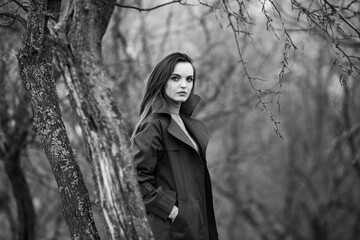 Image of young beautiful woman wearing rain jacket in cold weather. Thinker european girl in spring nature.