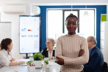 Successful smiling african business woman holding arms crossed looking atcamera in conference room. Manager working in professional start up financial business, modern company workplace ready for