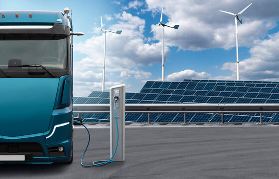 Electric Truck With Charging Station On A Background Of Solar Panels And Wind Turbines. Concept	