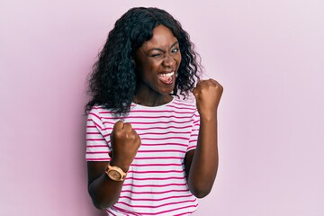 Beautiful african young woman wearing casual striped t shirt celebrating surprised and amazed for success with arms raised and eyes closed