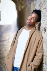 Young black man with a happy hopeful look on his face outdoors.