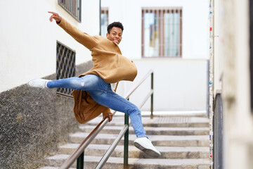 Cuban man jumping for joy over a handrail in the street.