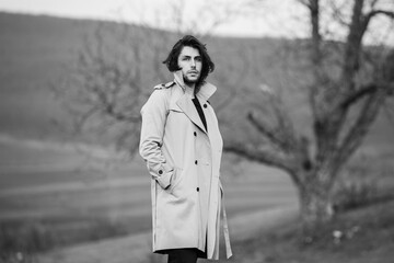 Image of young beautiful man with long hair wearing rain jacket in cold weather. Thinker european man in spring nature.