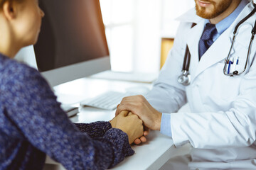 Friendly bearded doctor reassuring his female patient, close-up. Medical ethics and trust concept, medicine theme