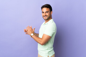 Young handsome man isolated on purple background applauding