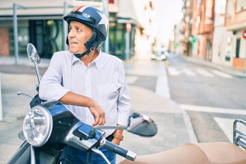 Fototapeta na wymiar Senior motorcyclist man smiling happy wearing moto helmet at the city.