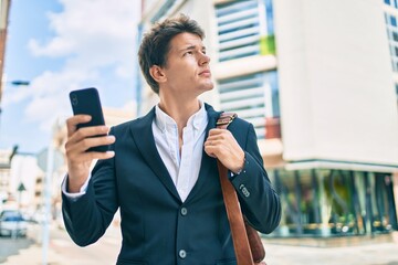 Young caucasian businessman with serious expression using smartphone at the city.