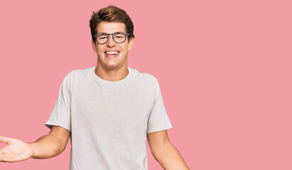 Obraz premium Handsome caucasian man wearing casual clothes and glasses smiling cheerful with open arms as friendly welcome, positive and confident greetings