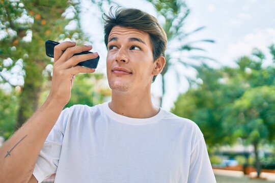 Young caucasian man smiling happy listening audio message using smartphone at the city.