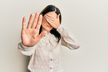 Middle age brunette woman wearing casual clothes covering eyes with hands and doing stop gesture with sad and fear expression. embarrassed and negative concept.
