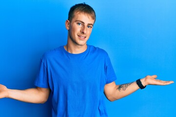 Young caucasian man wearing casual blue t shirt smiling showing both hands open palms, presenting and advertising comparison and balance