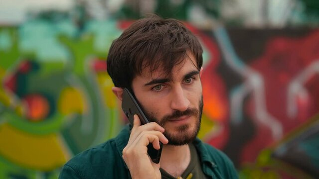 technology, communication - young man talks on phone looking around cautiously