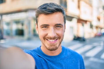 Young caucasian man smiling happy making selfie by the camera at the city.